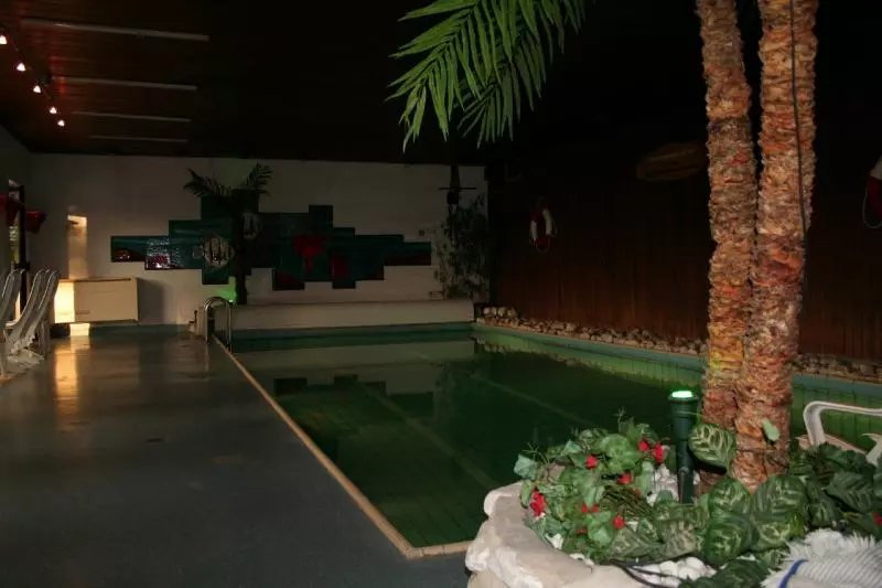 Innenbecken in einem Wellnessbereich mit Palmen und Sitzplätzen