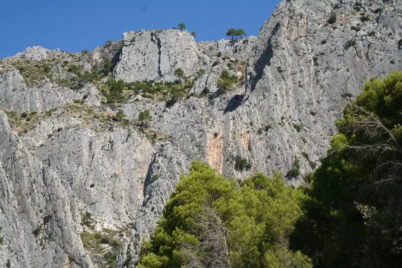 Steile Felswände mit kargem Bewuchs unter blauem Himmel