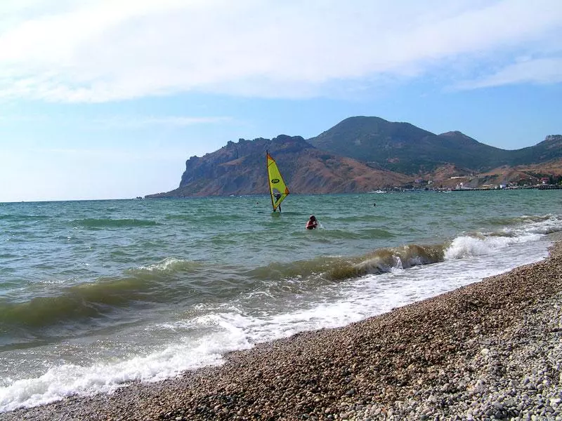Windsurfer vor einer bergigen Küste