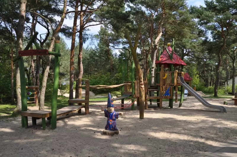 Spielplatz mit Klettergerüst und Rutsche im Kiefernwald