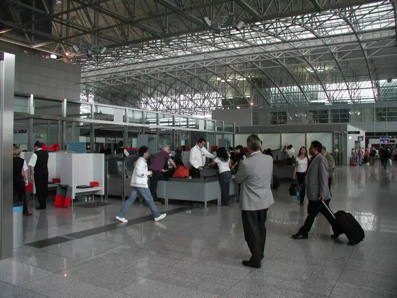Reisende mit Gepäck an einer Sicherheitskontrolle im Flughafen