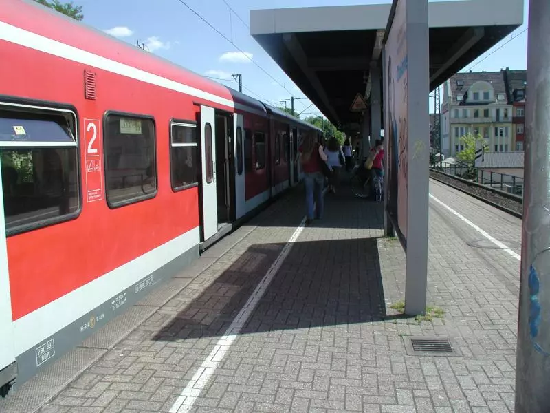 Reisende steigen an einem Bahnsteig in einen roten Zug ein