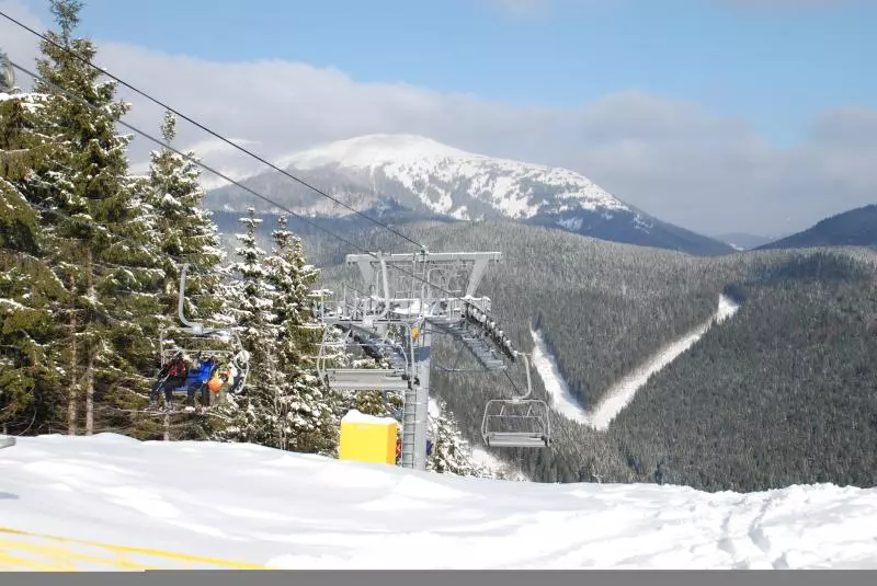 Zwei Skifahrer auf einem Sessellift in verschneiter Berglandschaft