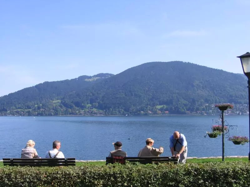 Menschen am See mit bewaldetem Berg im Hintergrund